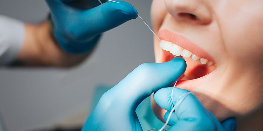 Dentist flossing a patient's teeth.
